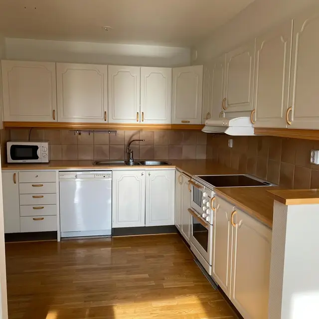 Kök med vita luckor och bänkskiva i trä under renovering