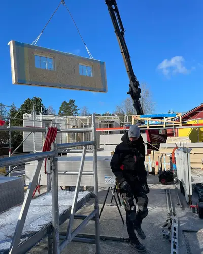 Prefabricerat väggelement lyfts på plats med kran