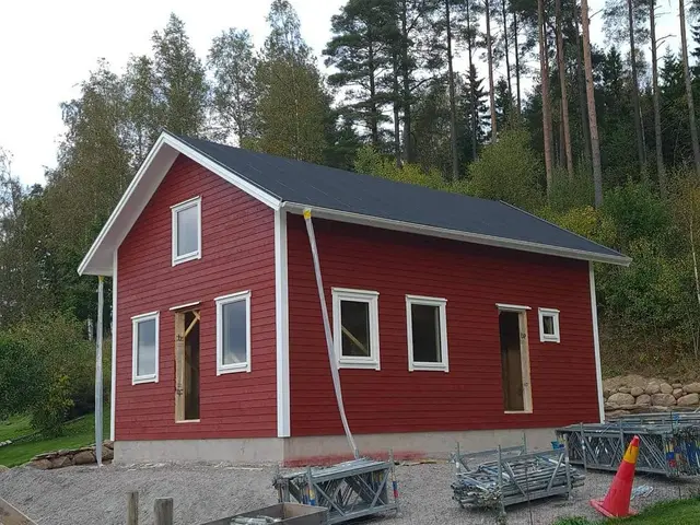 Nybyggd röd stuga med vita knutar